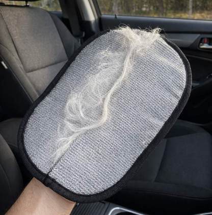 The Wagly glove held up inside a car, its grey pad holding a thick clump of pale dog hair lifted off the seats
