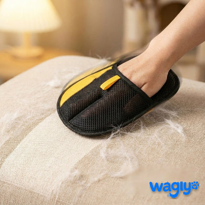 A hand in the Wagly glove sweeping pale pet hair off a beige fabric sofa